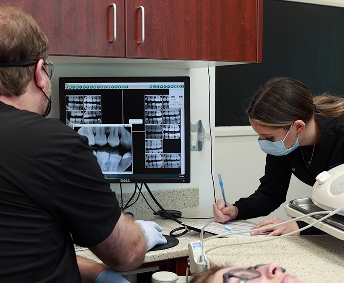 Dentist looking at charts of teeth using advanced dental technology