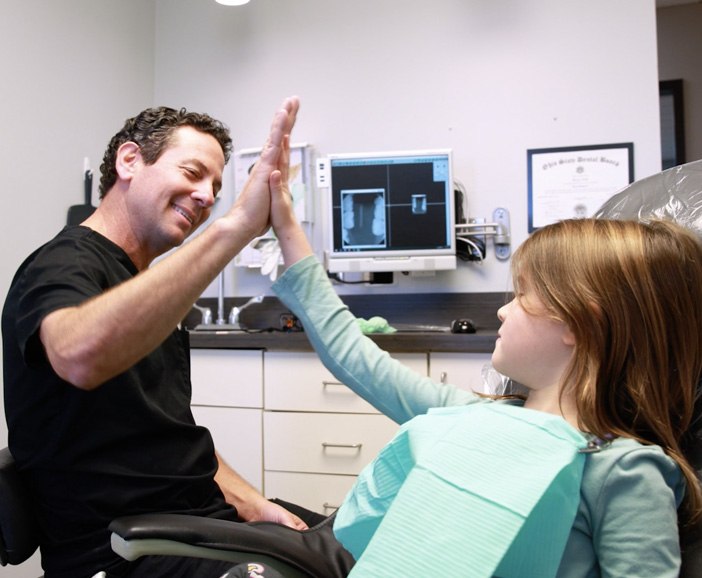 Doctor Tzagournis giving a young dental patient a high five
