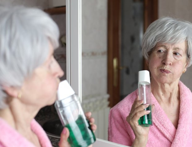 Dentures patient in Upper Arlington swishing with mouthwash