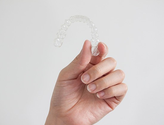 Patient in treatment chair holding clear aligner