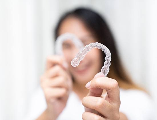 Smiling patient holding up clear aligners