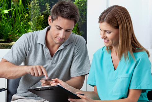 A young man paying the cost of wisdom tooth extractions